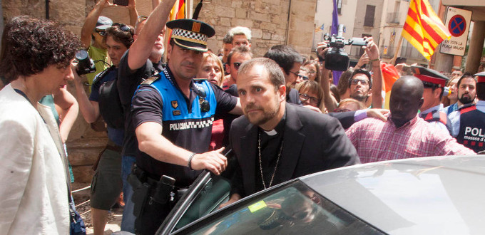 El obispo de Solsona sale de una iglesia escoltado por la policía entre gritos del lobby LGTBI